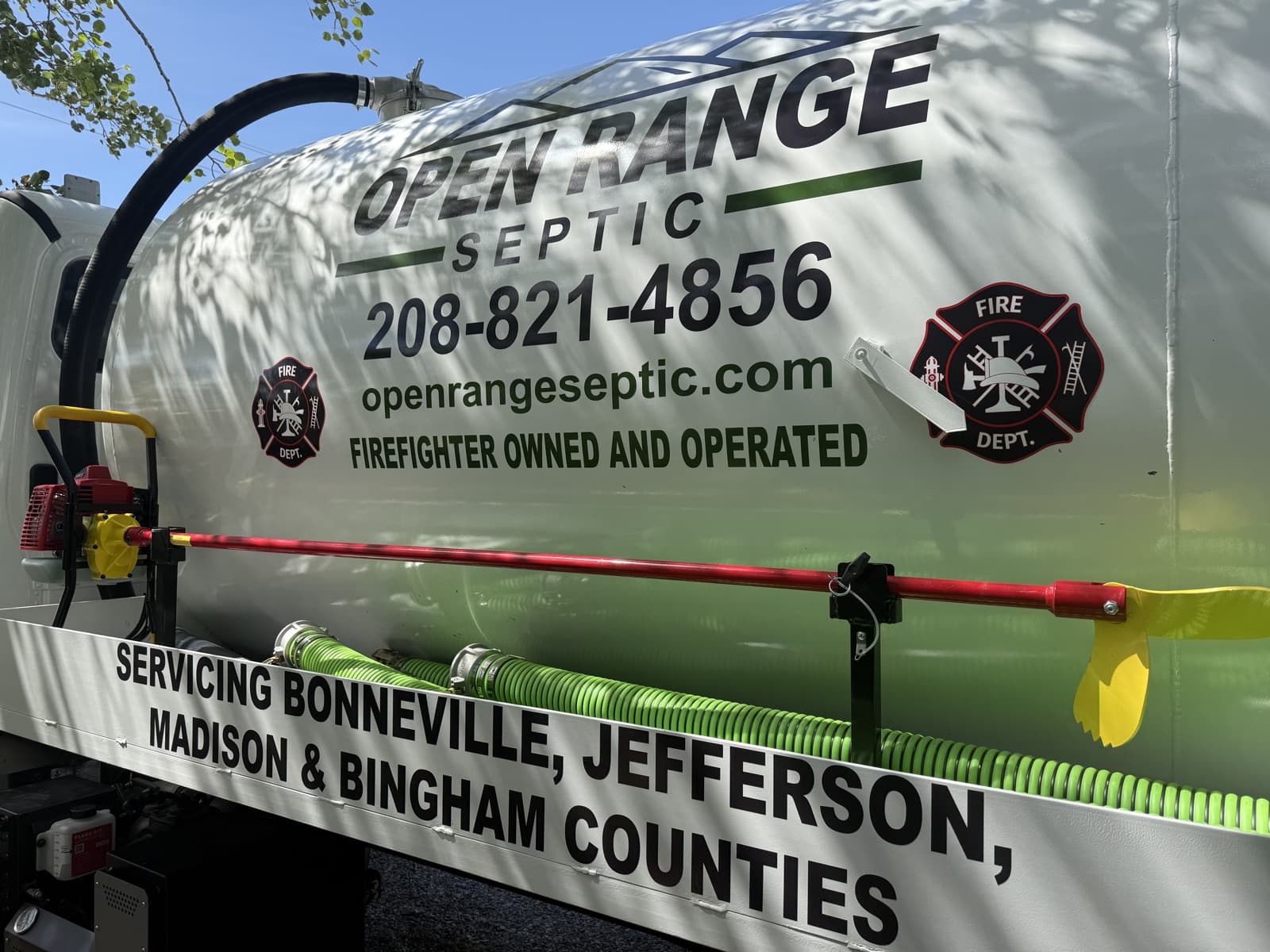 Open Range Septic tank branding with the service phone number and firefighter-owned message.